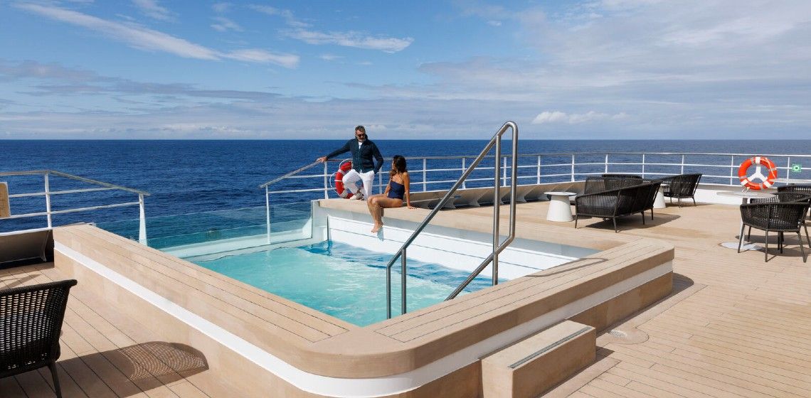 a man and woman sitting on a pool of water